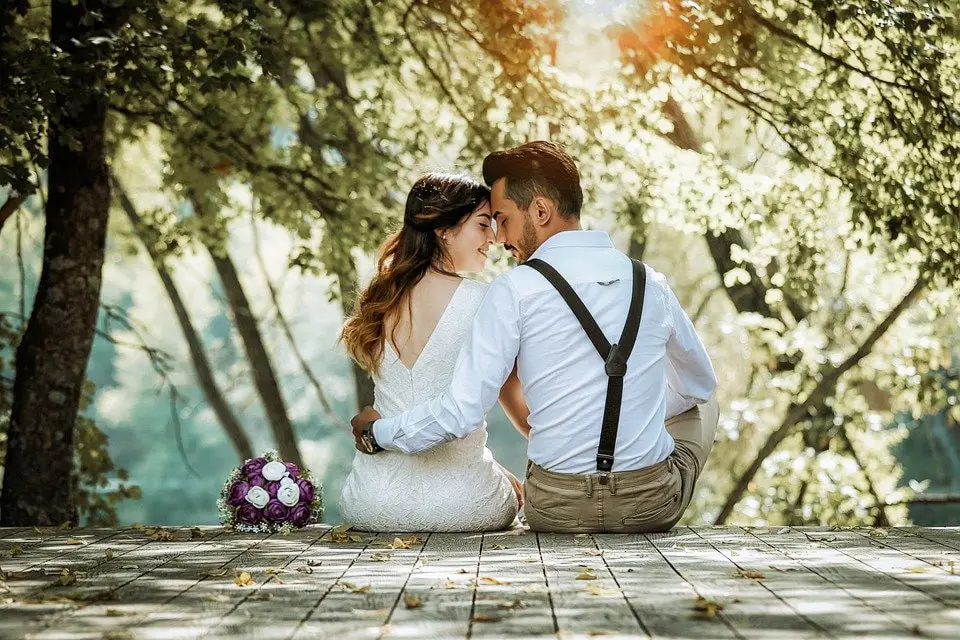 A newlywed couple sitting on a wooden bridge in the middle of nature